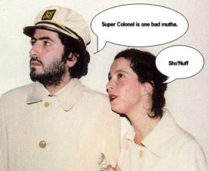 Daniel Bejar Destroyer wearing tan trench coat and captains hat with woman