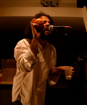 daniel-bejar-destroyer-wearing-white-shirt-singing-into-microphone-while-shaking-orange-googleganger-2 Daniel Bejar Destroyer wearing white shirt singing into microphone while shaking orange googleganger